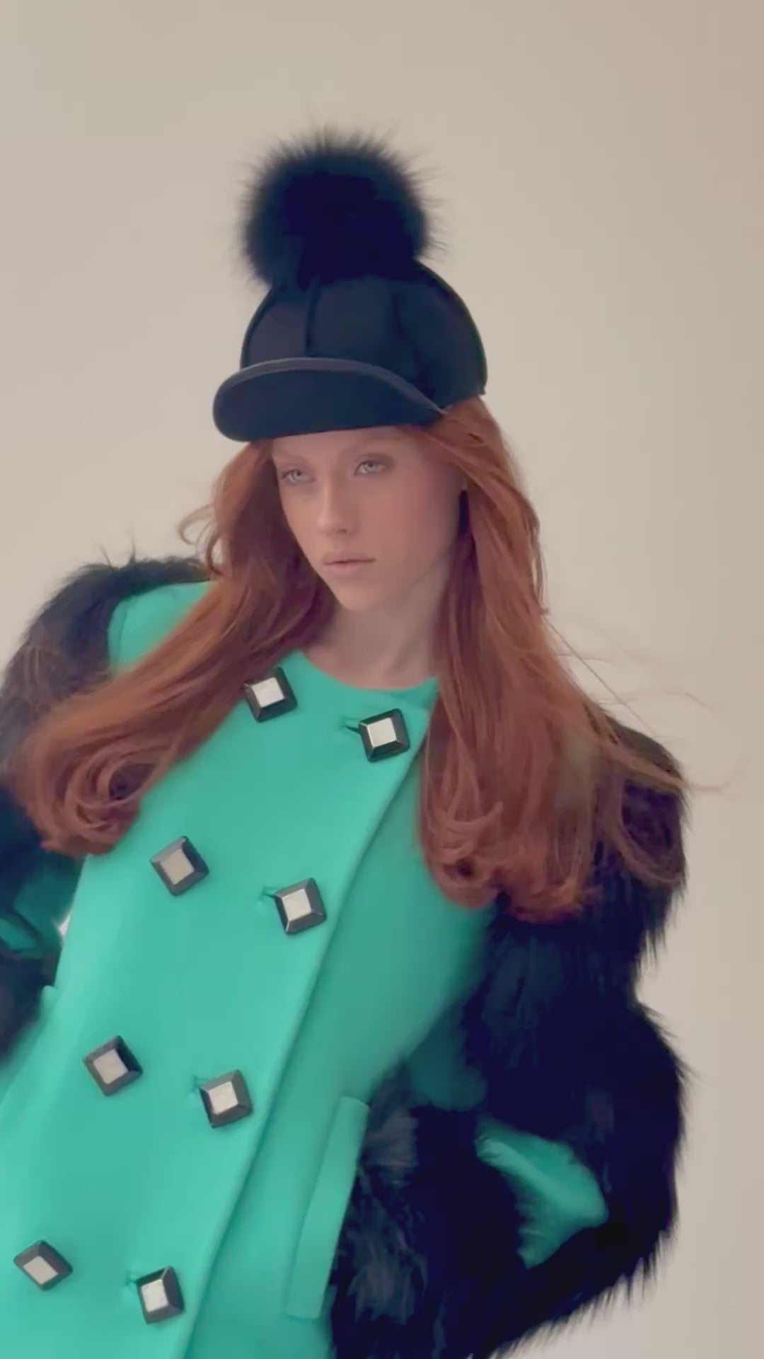 Woman wearing a Gucci green overcoat with black faux fur sleeves and bog buttons,